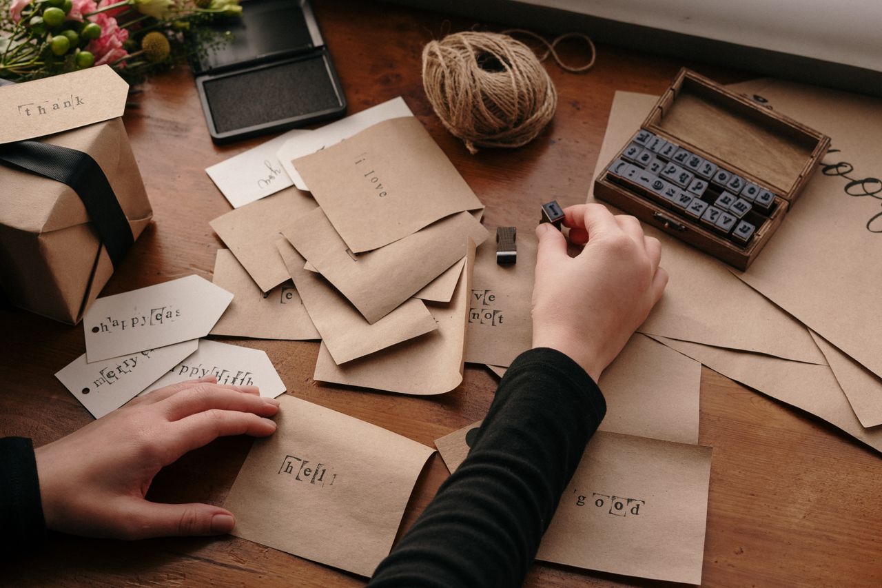 A person stamping envelopes with letters for handmade cards, showcasing creativity and craftsmanship.